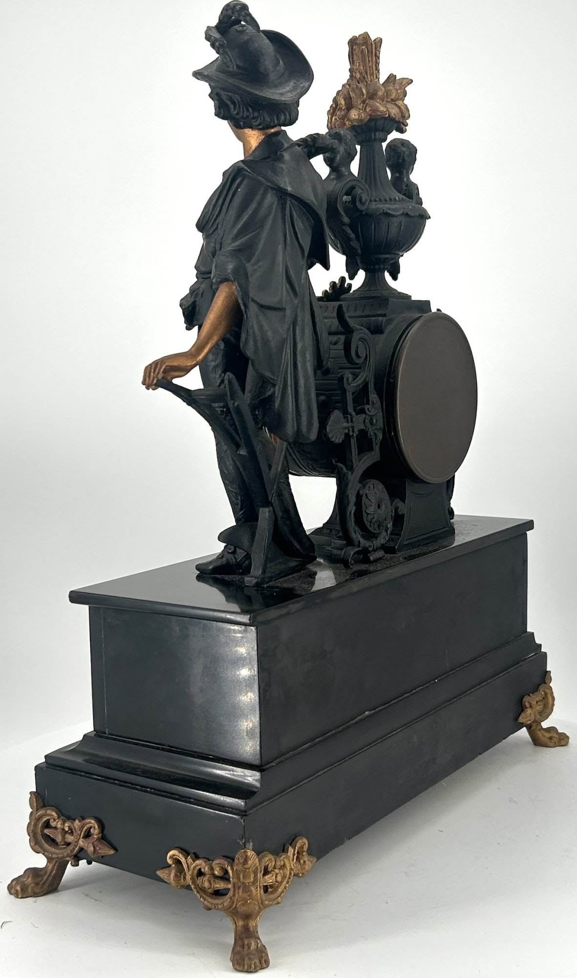 Wonderful original black ceramic dial with gilt roman numerals and hands. Presents on a slate base with a spelter figure and gilt inlaid etched decoration.
